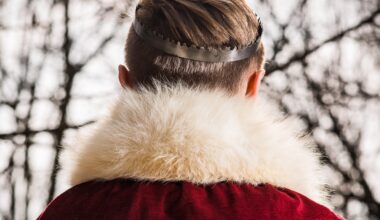 Titelbild: Ein*e König*in ist von hinten zu sehen. Sie*er trägt eine kleine Krone, einen roten Mantel mit weißem Pelzkragen und hat kurze, blonde Haare. Im Hintergrund sind verschwommen Äste zu sehen. (Foto: Pawel Furman auf Unsplash)