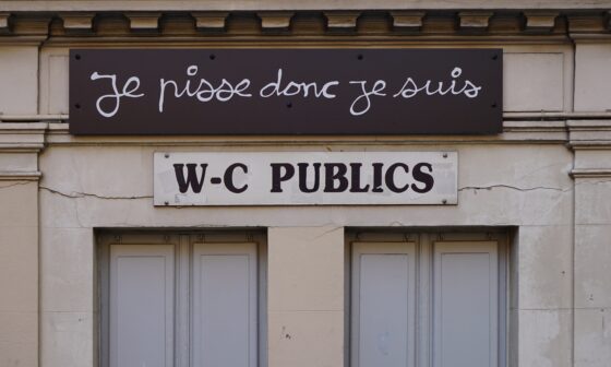 Eingang einer öffentlichen Toilette in Frankreich. Auf Französisch steht über dem WC-Schild "Ich pisse, also bin ich." (Foto: Tina Bosse auf Unsplash)