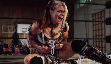 Die Wrestlerin Calypso sitzt bei der Frauen-Wrestling-Veranstaltung „Breaking Barriers“ auf dem Ringboden und ballt schreiend die Fäuste. Sie trägt schwarz-weiß-goldene Wrestling-Kleidung. (Foto: Nadine Veigel/Photos N Effect)