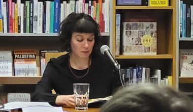 In dunkler Kleidung sitzt Sarah Lorenz vor einem Bücherregal in der Freiburger Buchhandlung Schwarz und liest aus ihrem Roman „Mit dir, da möchte ich im Himmel Kaffee trinken“ vor. (Foto: vliestext)