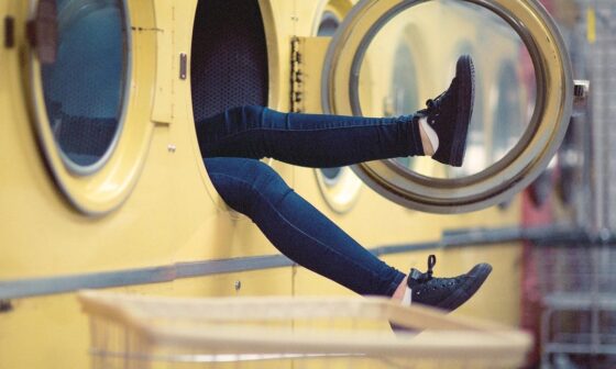 In einem Waschsalon schauen die Beine einer Person aus einer Waschmaschine heraus. (Bild: Pexels auf Pixabay)