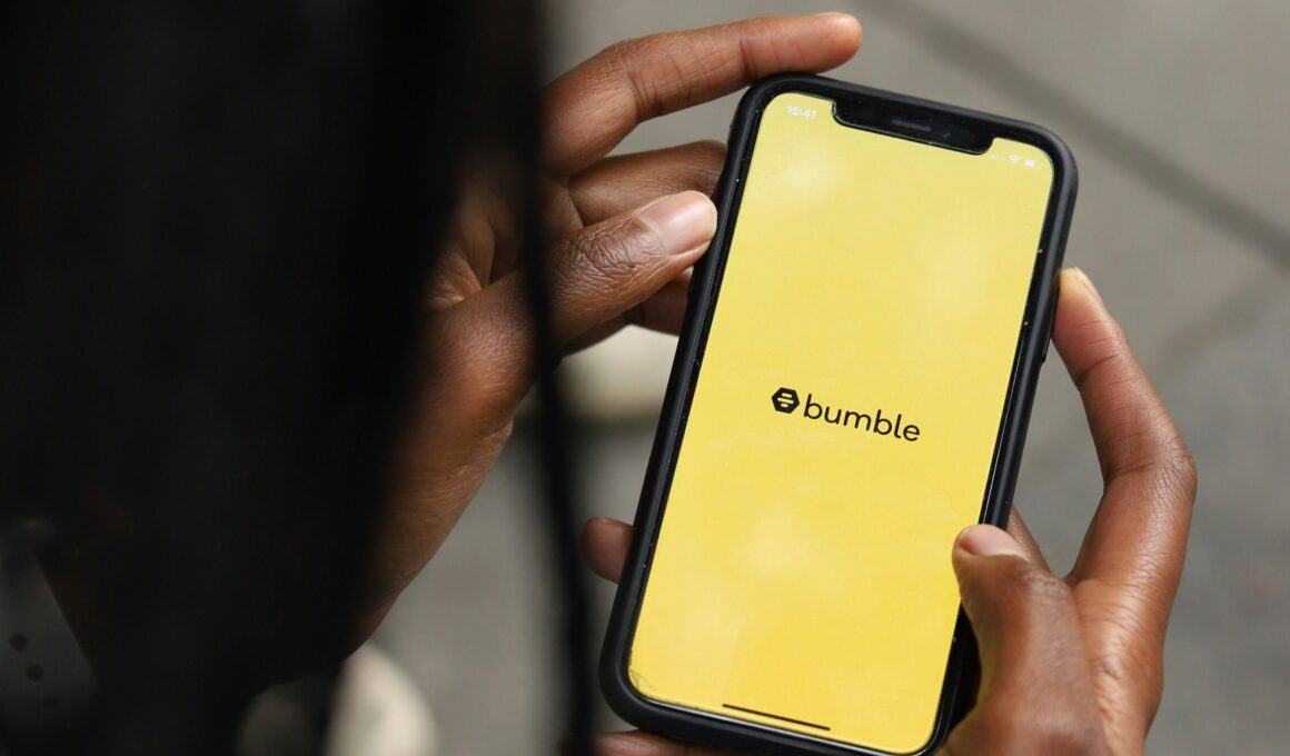 Schwarzer Mensch schaut auf Handy-Bildschirm, auf dem das gelbe Bumble-Logo zu sehen ist. (Bild: Good Faces Agency auf Unsplash)