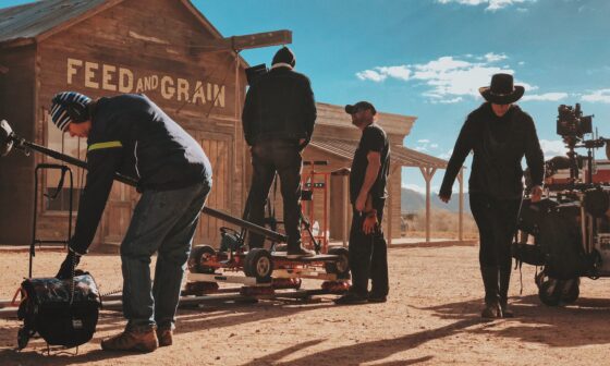 In den Kulissen einer Western-Stadt arbeitet eine Film-Crew mit ihrer Ausrüstung und bereitet eine Szene vor. Im Hintergrund blauer Himmel. (Bild: Chris Murray auf Unsplash)