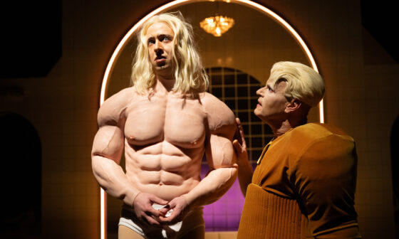 Szene aus dem Theaterstück „Pretty Privilege“ (Schauspiel Stuttgart): Neben dem fast nackten, muskelbepackten Dorian (Tim Bülow) steht Basil (Sebastian Röhrle) und schaut zu ihm auf. (Foto: Björn Klein)