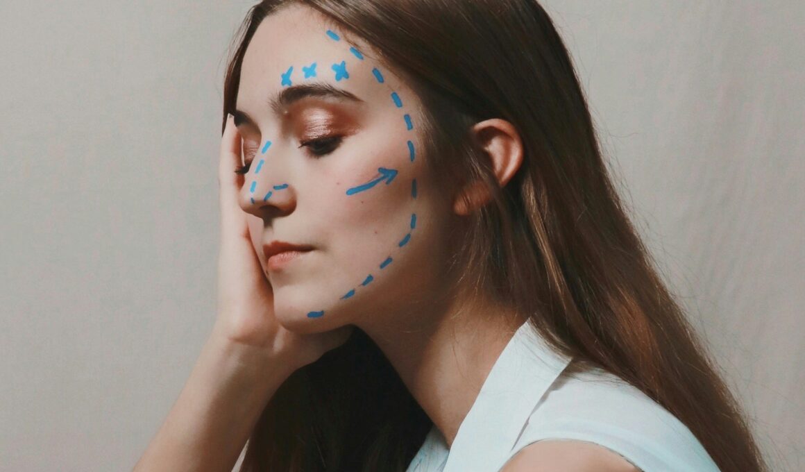 Mensch mit langen braunen Haaren schaut nachdenklich nach unten. Der Kopf ist mit einer Hand abgestützt. Im Gesicht finden sich blaue Markierungslinien, wie man sie von Schönheitsoperationen kennt. (Foto: Joeyy Lee auf Unsplash)