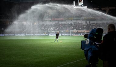 Rasen eines Fußballstadions bei Nacht. Darauf ein einzelner Fußballer, am Rand eine TV-Kamera-Station, auf den Spieler gerichtet. (Foto: Maxim Hopman)