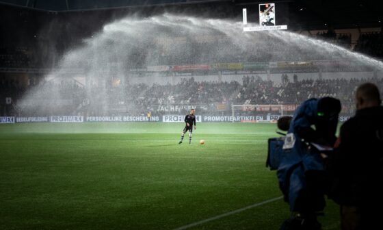 Rasen eines Fußballstadions bei Nacht. Darauf ein einzelner Fußballer, am Rand eine TV-Kamera-Station, auf den Spieler gerichtet. (Foto: Maxim Hopman)